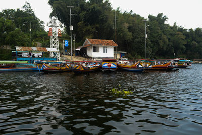 Boats moored in water against sky