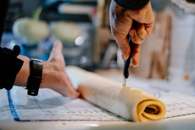 Close up of human hand cutting cake dough