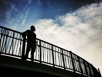 Low angle view of people standing on railing