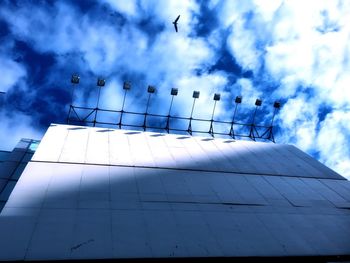 Low angle view of birds flying against cloudy sky