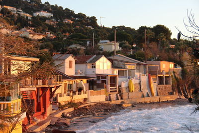 Houses by buildings against sky during sunset