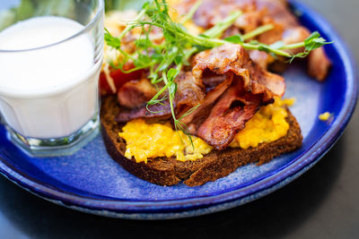 Very bright and healthy breakfast on a plate - bacon, egg, salad, tomato, cheese, a glass of yogurt