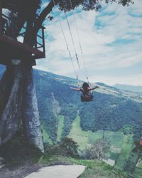 Low angle view of man hanging on mountain against sky