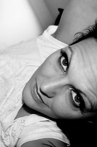 Close-up portrait of young woman relaxing on bed at home