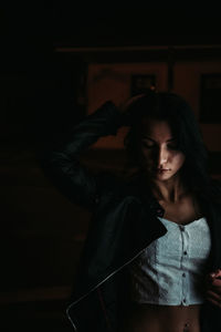 Young woman looking down while standing in dark room