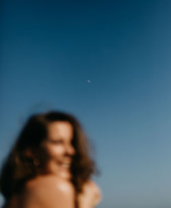 Blurred unrecognizable woman against blue sky at dusk