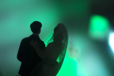 Silhouette man and woman standing against illuminated stage