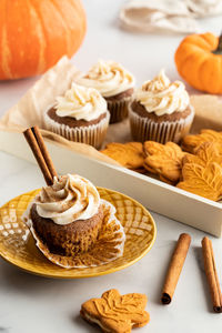 A tray of pumpkin spice cupcakes and cookies with a cupcake on a plate in front.