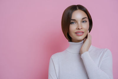 Portrait of young woman standing against wall
