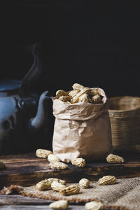 Close-up of peanuts in paper bag with kettle on table