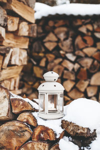 Lantern on stacked logs during winter