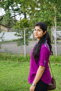 Portrait of young woman standing at park