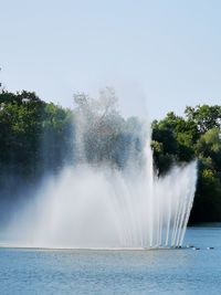 Water splashing in fountain against clear sky