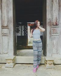 Portrait of smiling young woman standing against wall