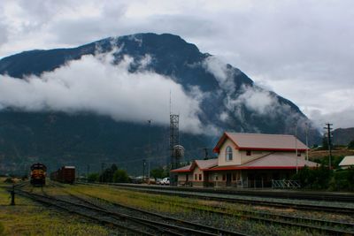 House by railroad tracks against mountain