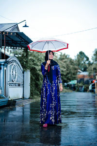 Rear view of woman with umbrella standing in city