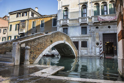 Arch bridge over canal amidst buildings in city