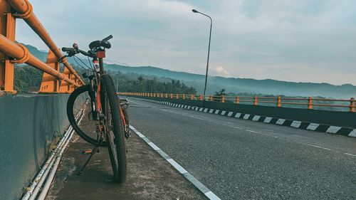 Man riding bicycle on road against sky