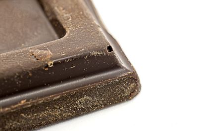 Close-up of chocolate cake on metal against white background
