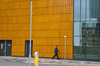 Rear view of man walking on yellow building