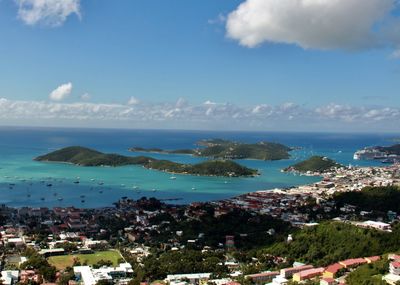 Aerial view of townscape by sea against blue sky