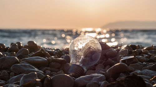 Close-up of pebbles on beach against sky during sunset