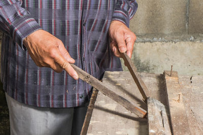 Midsection of worker holding wood in workshop