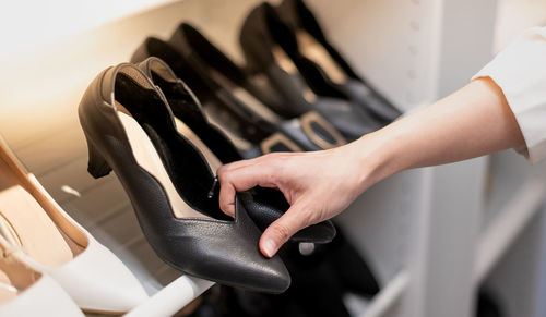 The woman holding shoes in her hands to choose, shopping looking at the shelves with footwear.