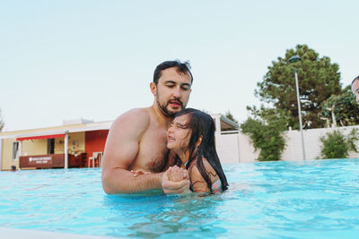 Portrait of father holding daughter in swimming pool