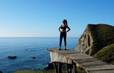 Woman standing on footpath against sea