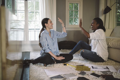 Happy design professionals giving high-five while working at home