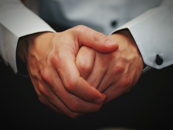 Midsection of man with hands clasped