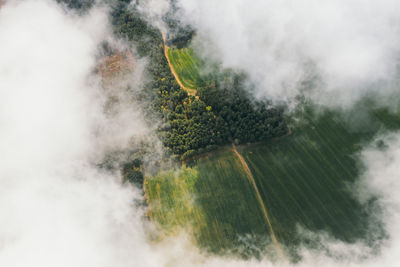 Landscape view from drone, green fields, sky with white clouds.