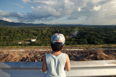 Rear view of boy standing against landscape