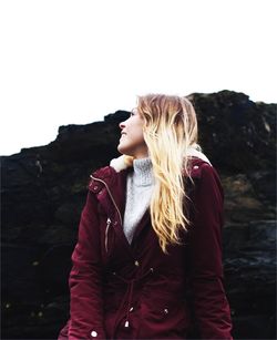 Young woman standing on rock against sky