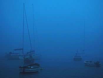 Sailboats sailing in sea against sky at dawn