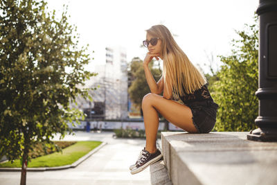 Young woman in sunglasses against trees in city