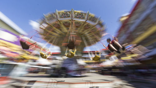 Boy sitting on spinning carousel at amusement park