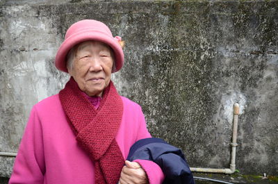 Portrait of senior woman wearing hat against wall