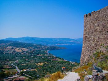 Scenic view of sea and mountains against clear blue sky