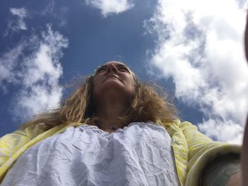 Low angle view of mature woman standing against sky