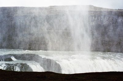 Scenic view of waterfall against sky