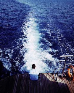 Rear view of man sitting on boat in sea