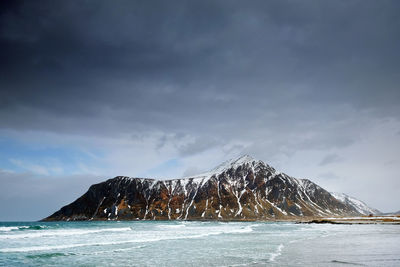 Scenic view of sea by snowcapped mountain against sky