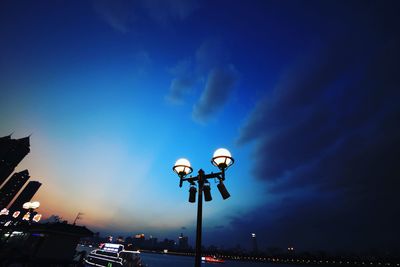 Low angle view of illuminated street light against blue sky