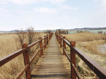 View of wooden footbridge against sky