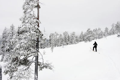 Woman walking on snow covered land against sky