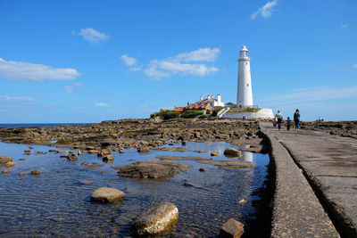 Lighthouse by sea against sky