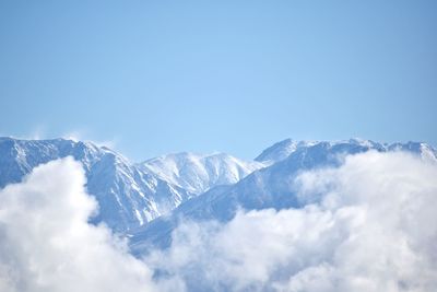 Low angle view of snowcapped mountains against blue sky
