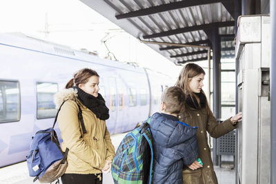 High school students buying tickets from automated machine at train station